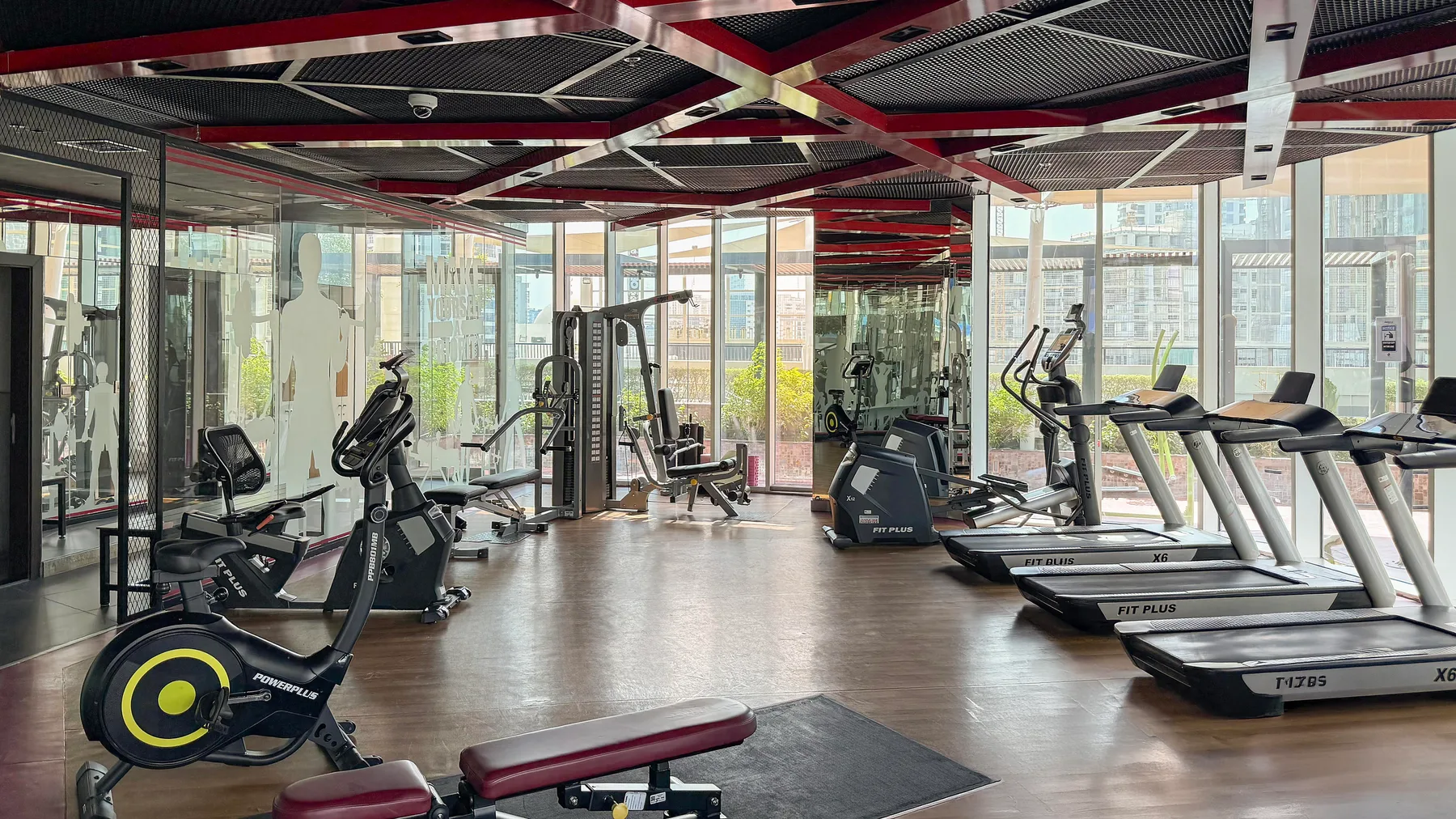 Un gimnasio con bicicletas estáticas, máquinas de pesas y cintas junto a grandes ventanales.