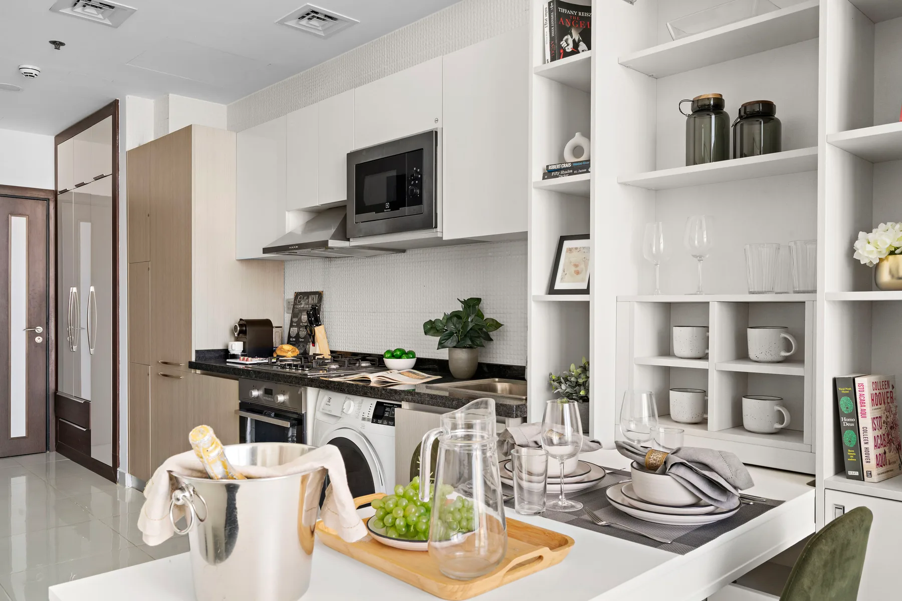 Una cocina luminosa con gabinetes blancos, una encimera y una mesa puesta.