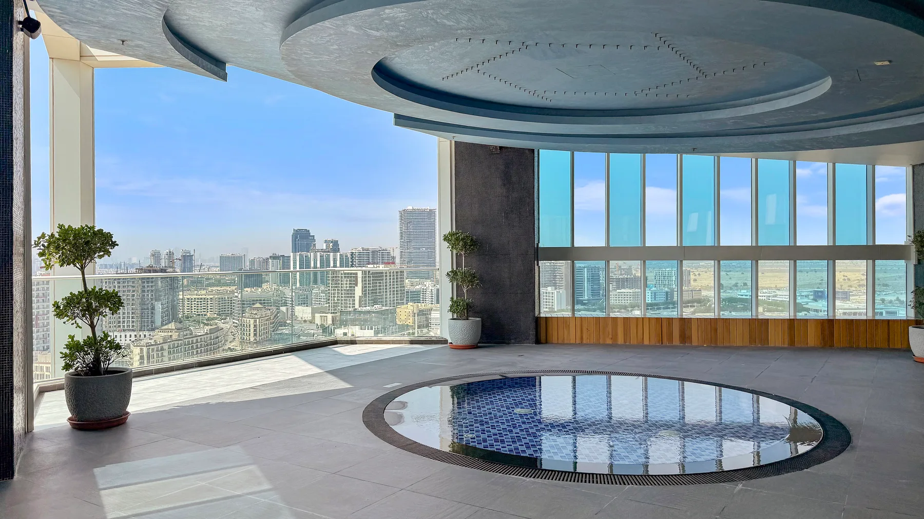 Una piscina circular interior está junto a ventanales con vistas a la ciudad.