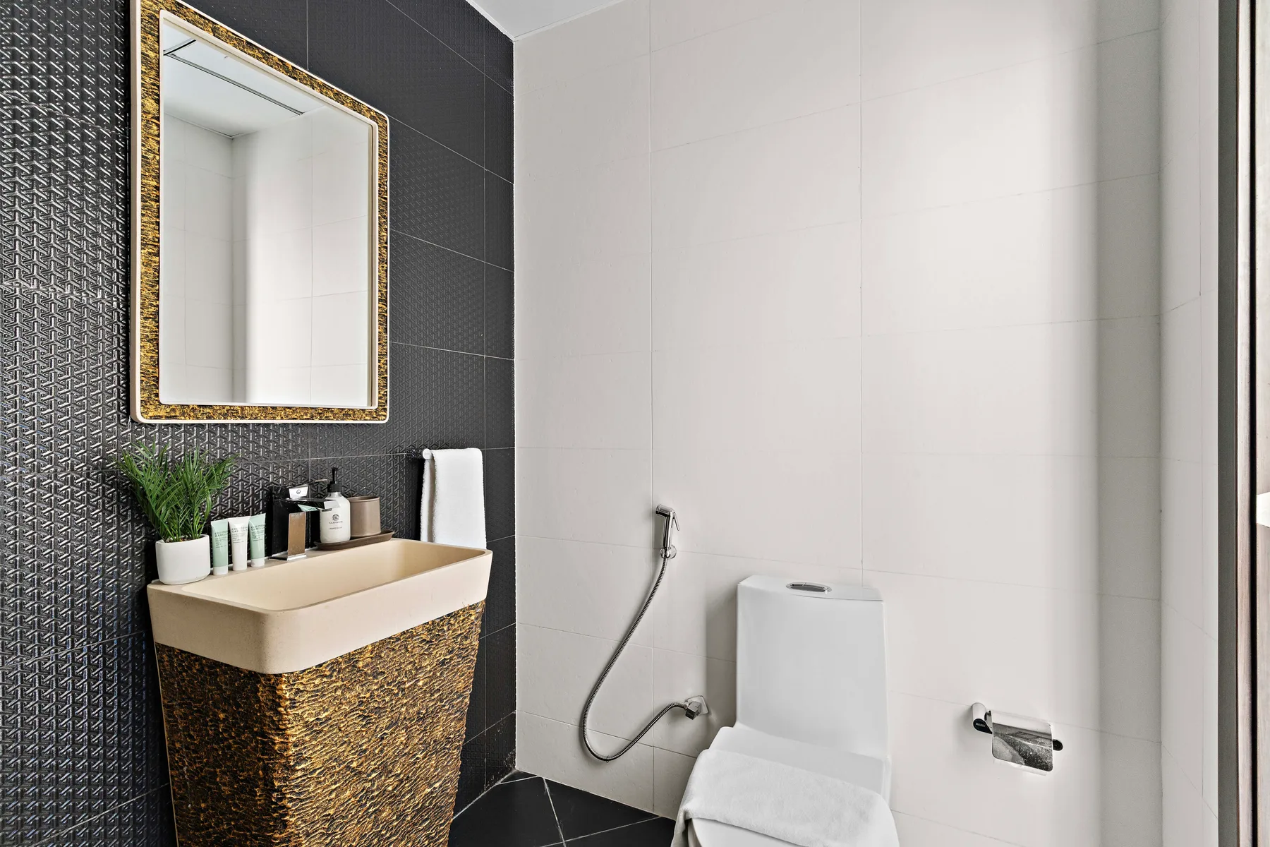 Un baño moderno con lavabo sobre encimera, espejo de pared e inodoro.