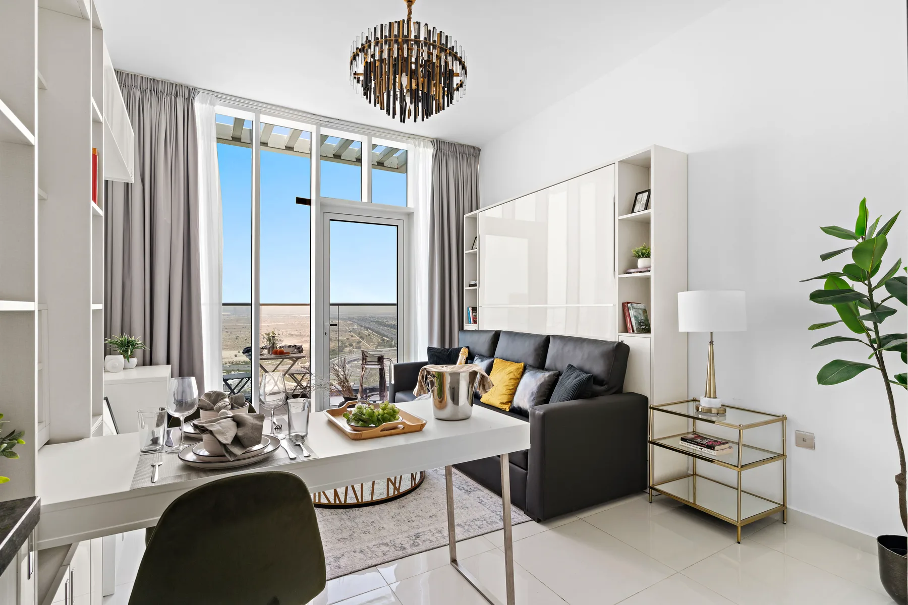 Una sala luminosa con mesa de comedor, asientos y ventanas altas con vista a un balcón.