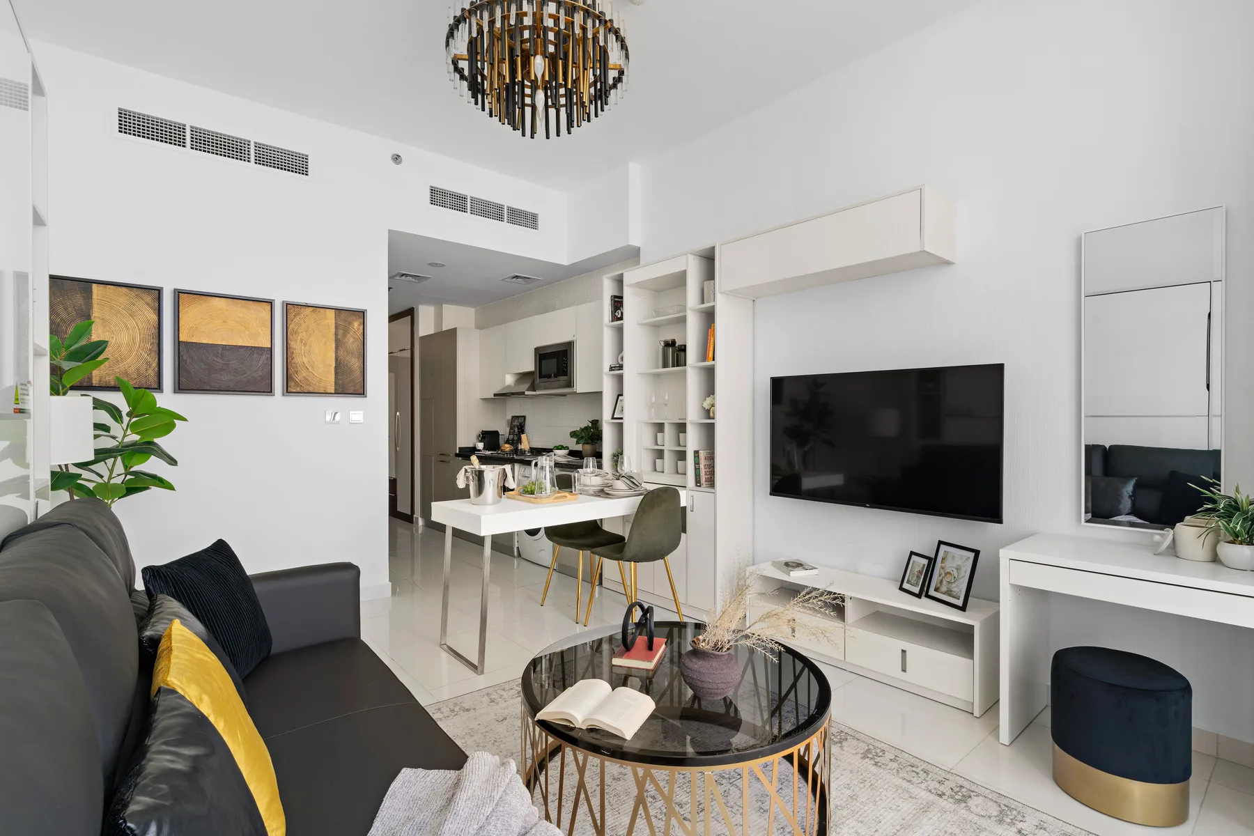 Una sala luminosa con televisor, asientos y una cocina abierta.