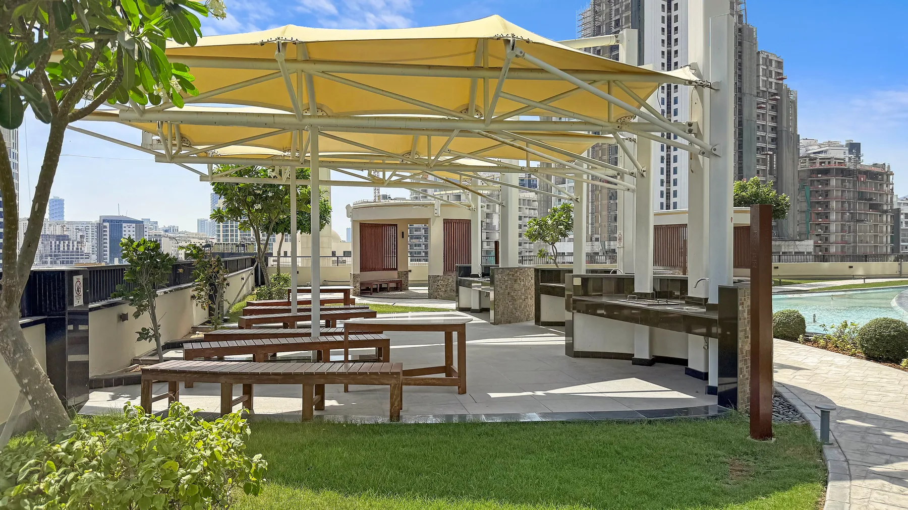 Una terraza exterior en la azotea con asientos bajo un toldo amarillo.