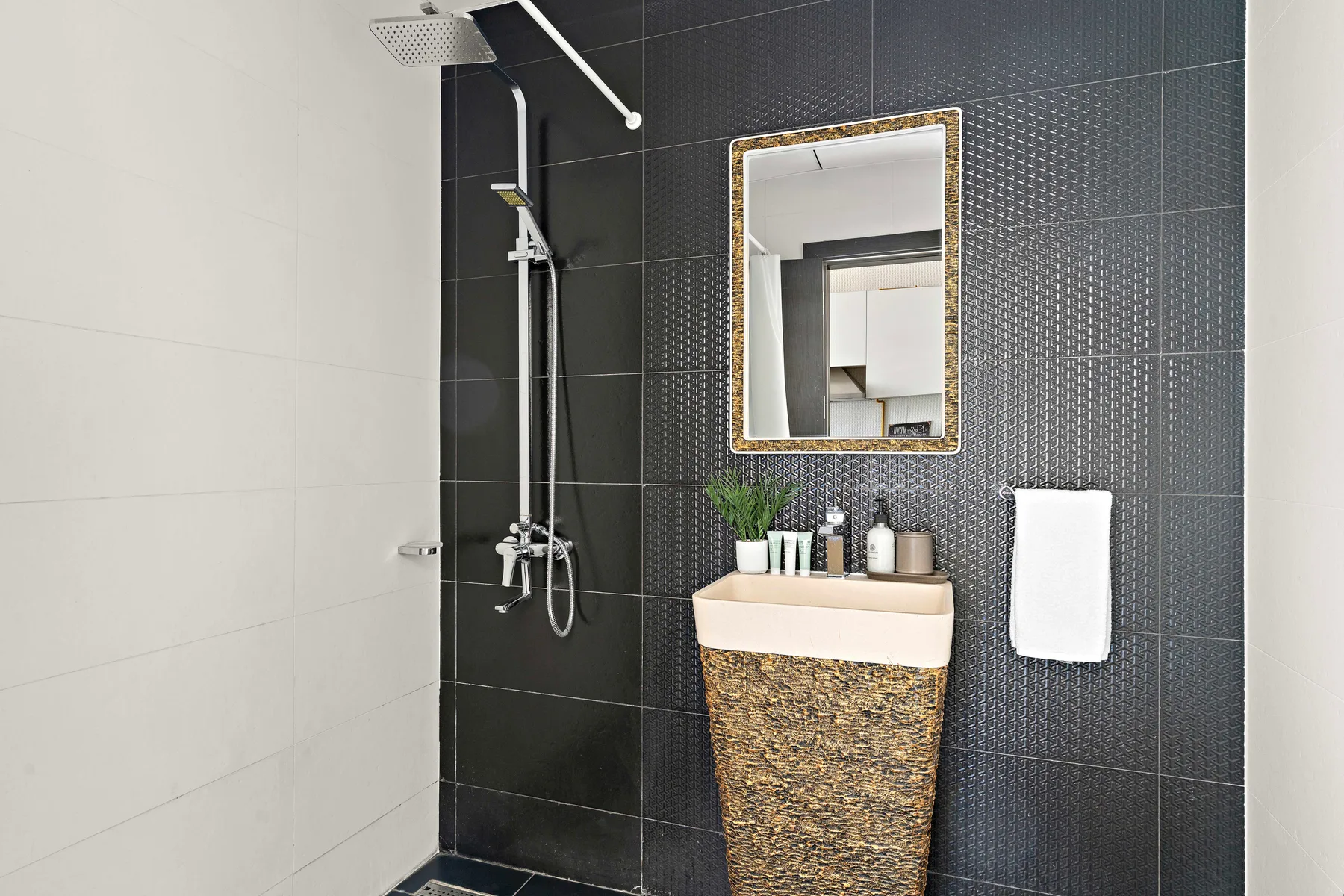 Un lavabo de baño y una ducha destacan sobre paredes de azulejos contrastantes.