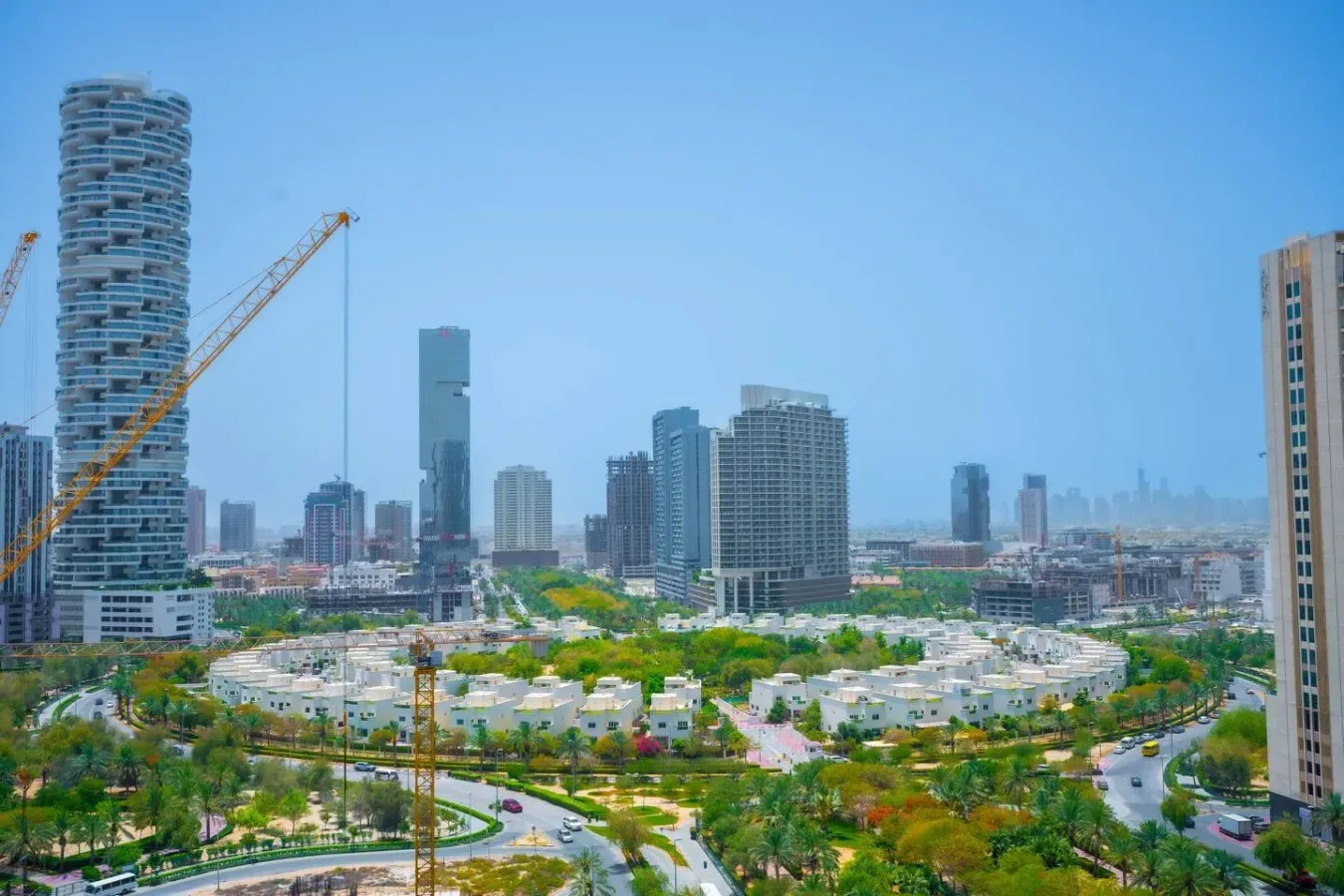 El horizonte urbano se alza detrás de edificios bajos, árboles y zonas ajardinadas.