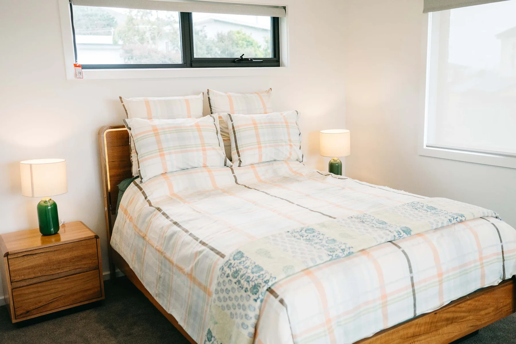 A bedroom with a neatly made bed and matching bedside tables.