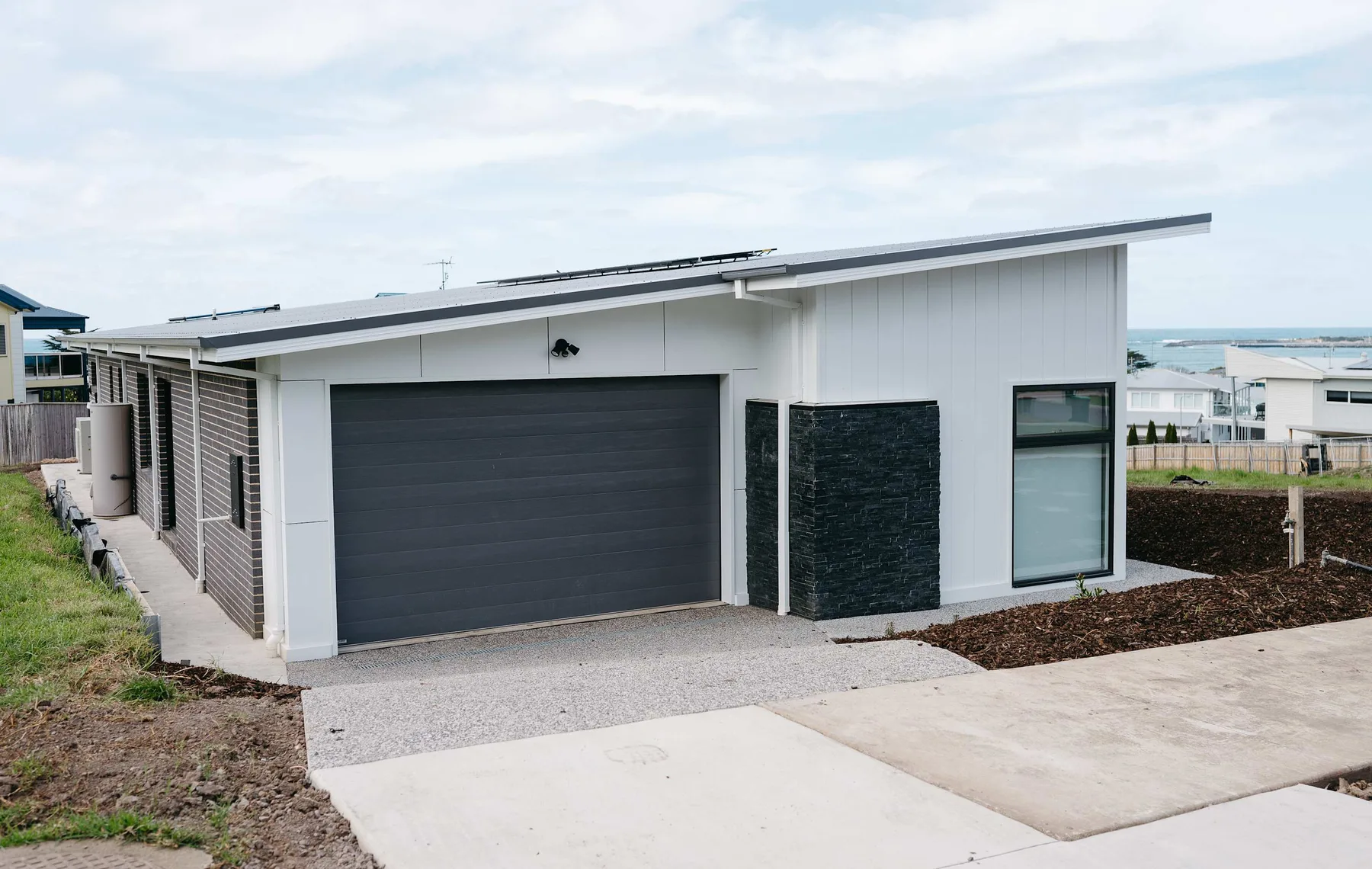 A modern house exterior with a wide garage door and driveway.