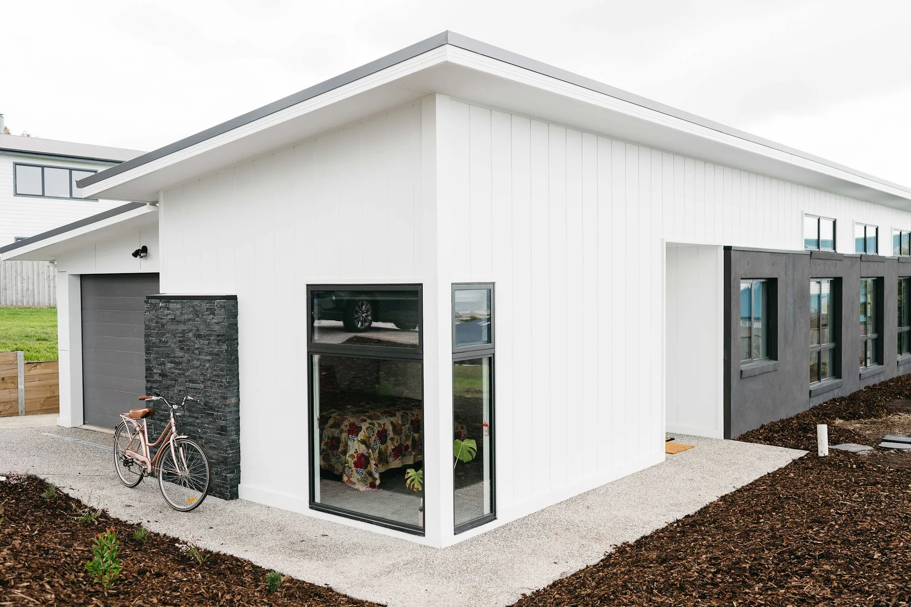 A modern white building with large windows beside a gravel walkway.