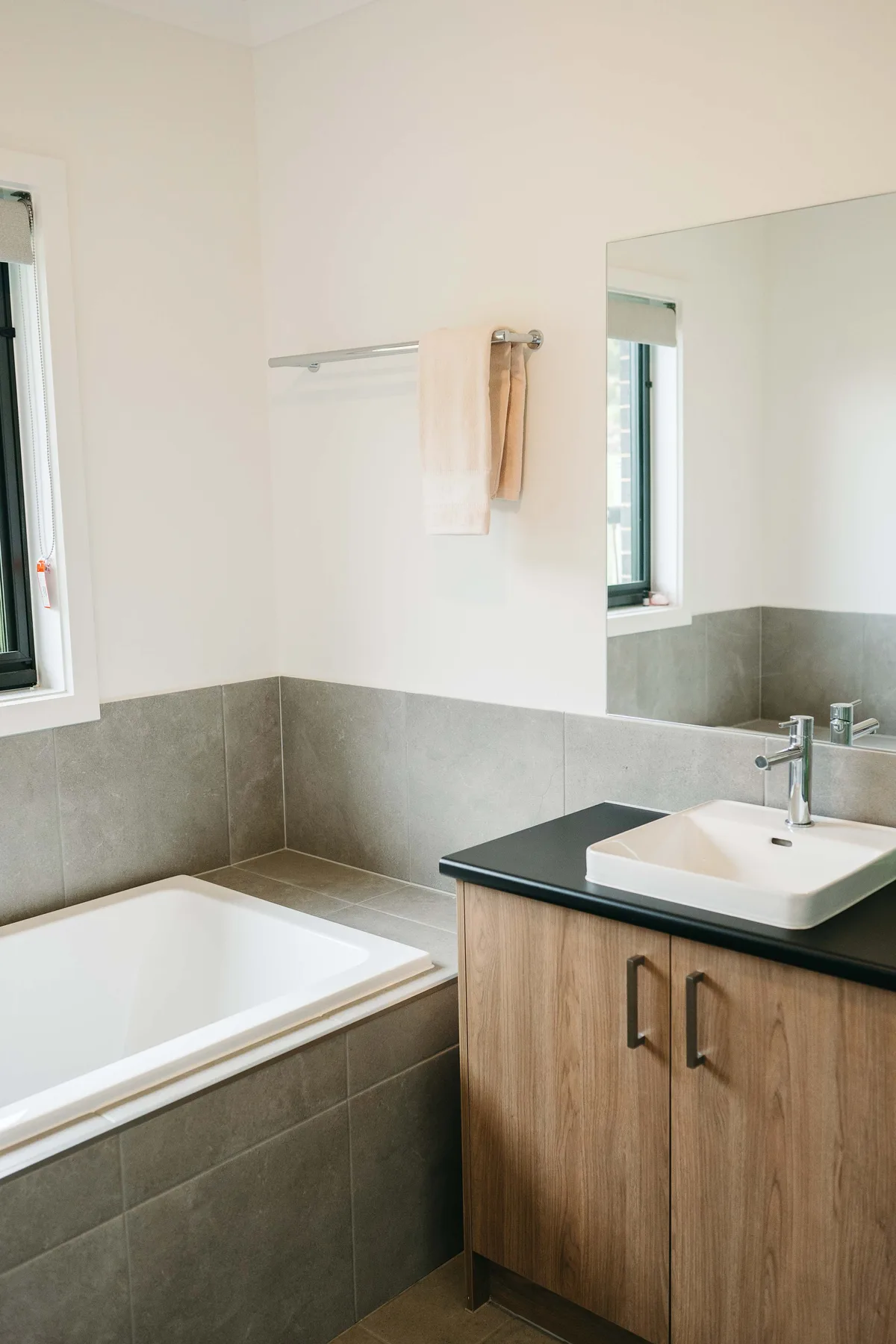 A bathroom with a bathtub, vanity, and large mirror.