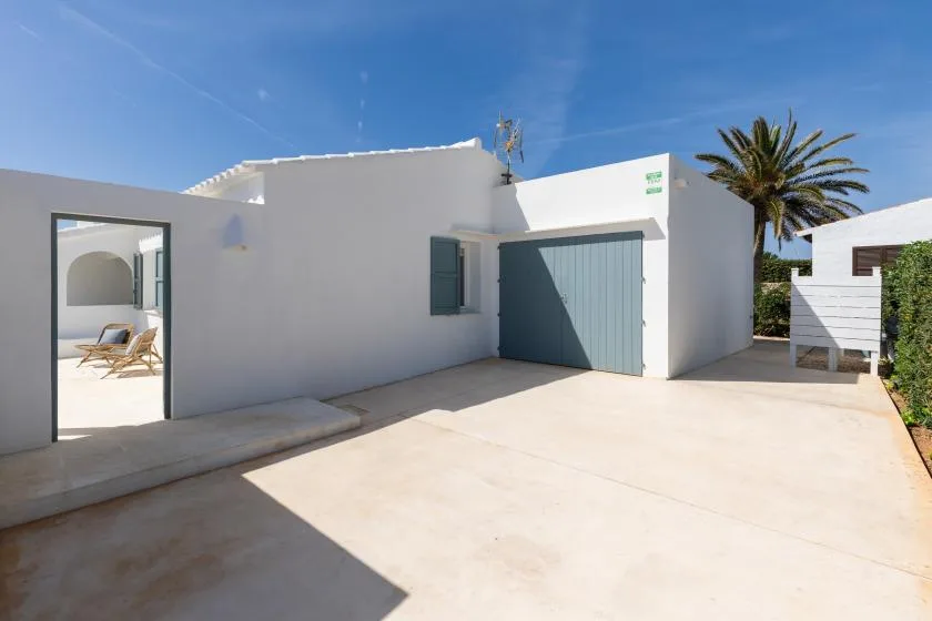 A white building opens onto a sunlit paved courtyard.