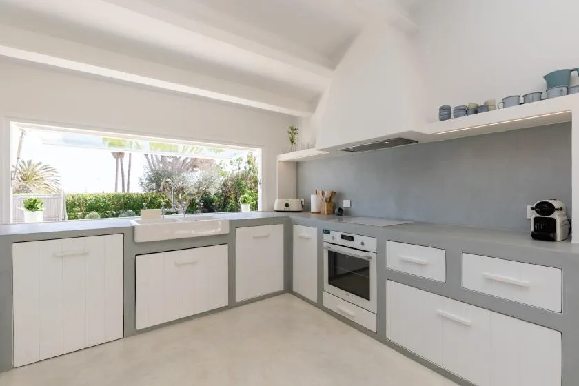 A bright kitchen with gray countertops and a wide window overlooking greenery.