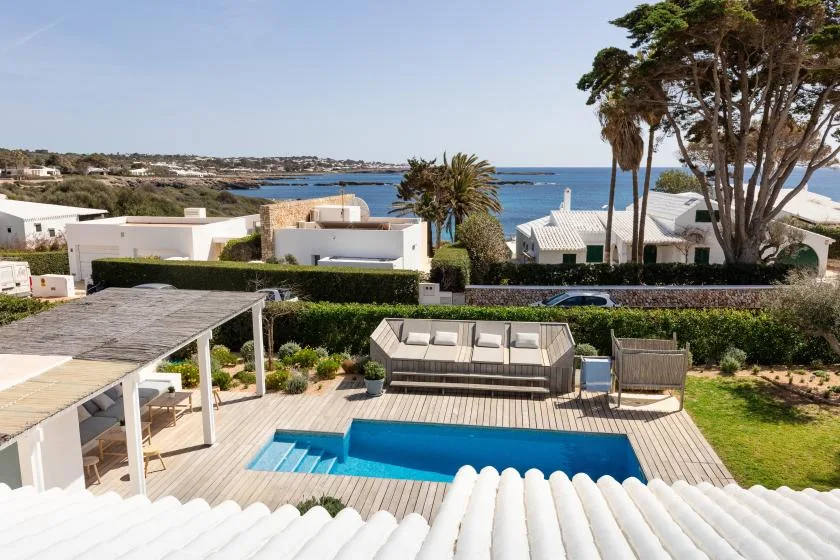 A swimming pool and outdoor seating overlook the coastline.