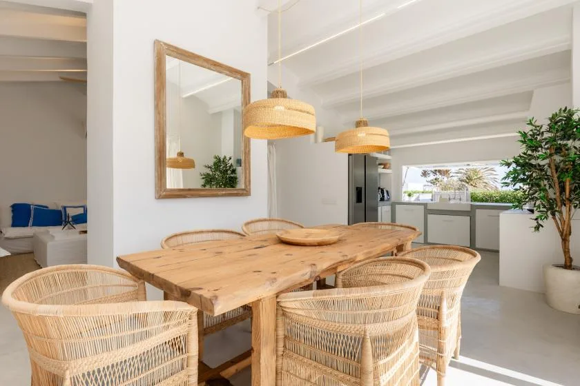 A dining area with a wooden table and woven seating beside the kitchen.