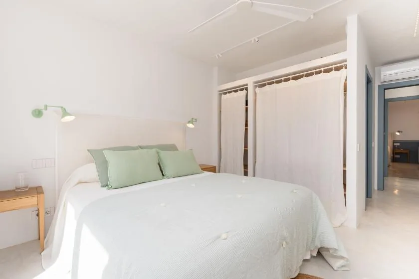 A bright bedroom with a white bed and pale green pillows.