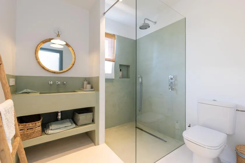 A bathroom with a glass shower, sink counter, and toilet.