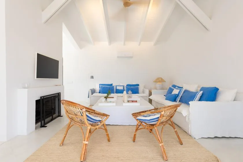 A bright living room with white seating, blue cushions, and a low coffee table.