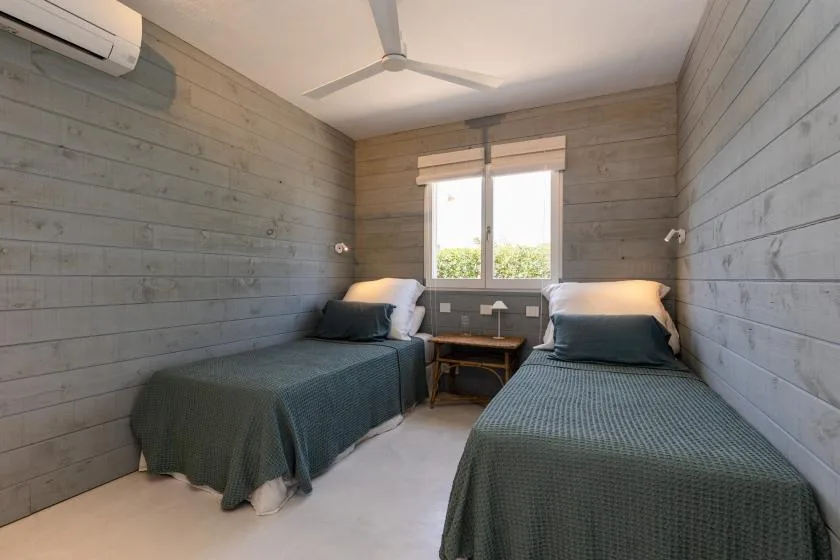 A bedroom with two beds and a window between them.
