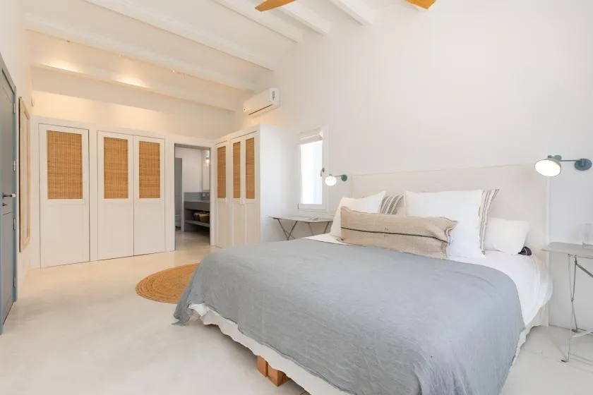 A bright bedroom with a large bed and built-in wardrobes.
