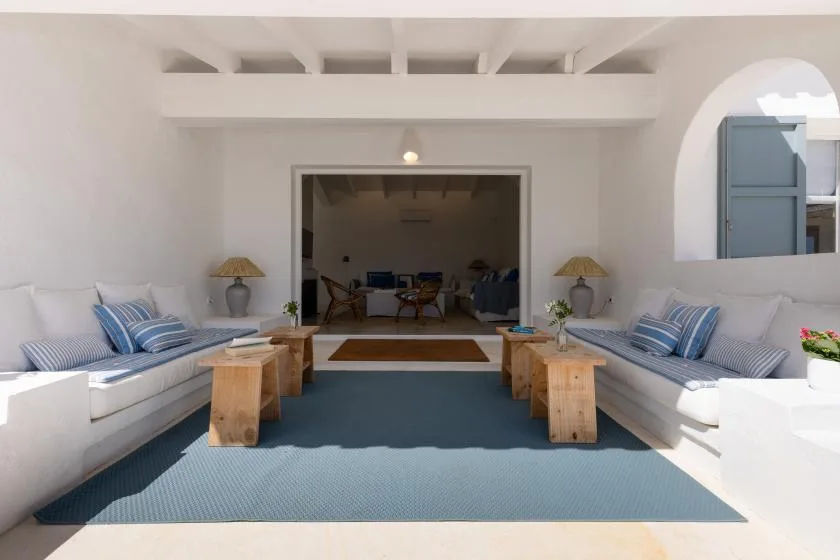 A bright lounge with built-in seating, wooden tables, and a blue rug.