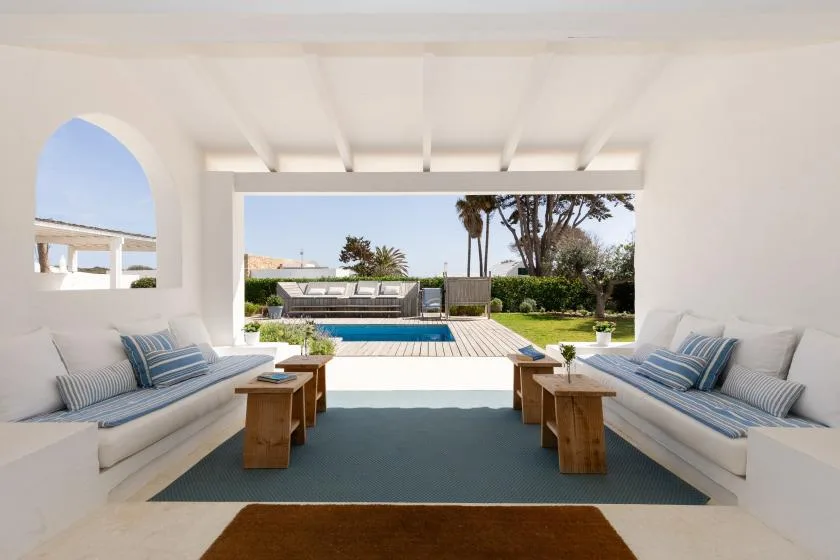 A covered outdoor seating area opens onto a swimming pool and garden.