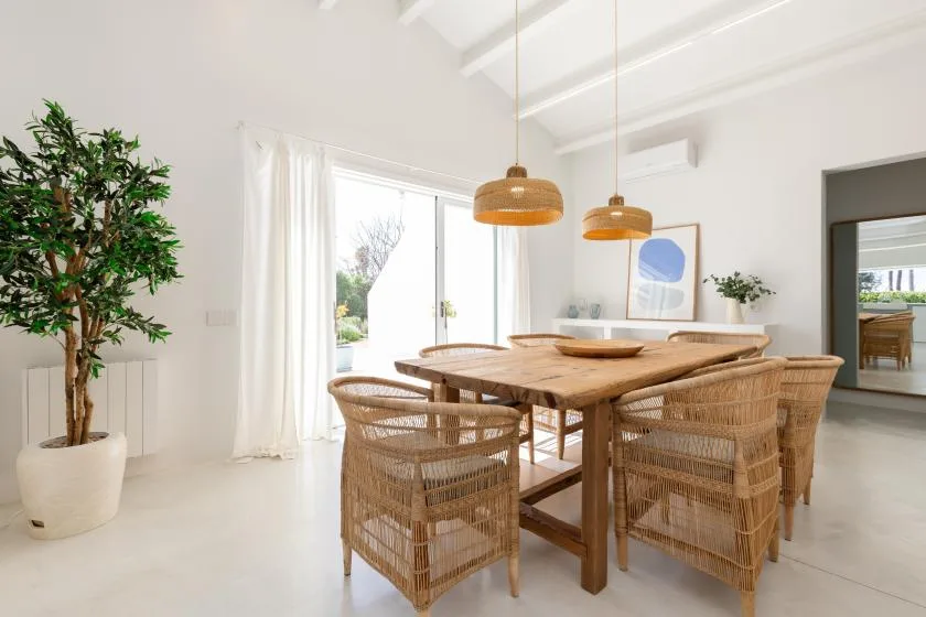 A bright dining area with a wooden table and woven seating.