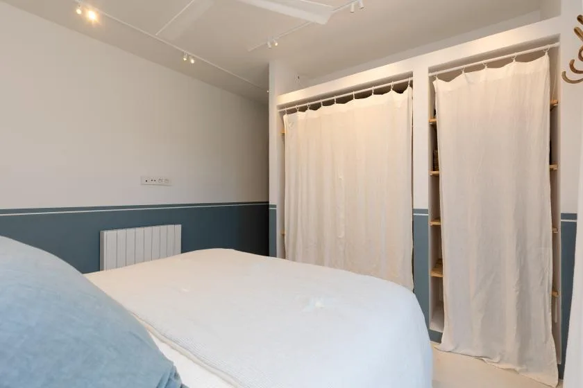 A bedroom with a bed and curtained storage alcoves along the wall.