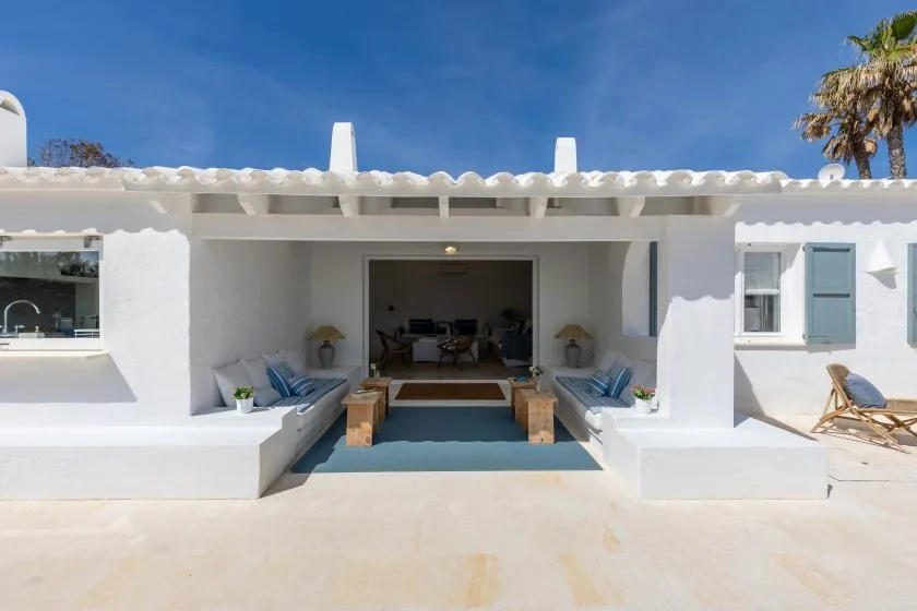 White stucco house with a shaded outdoor seating area beside the open living room.
