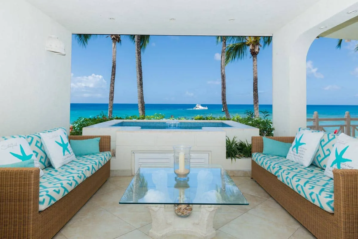 An open-air lounge with patterned seating overlooks a pool and the ocean.