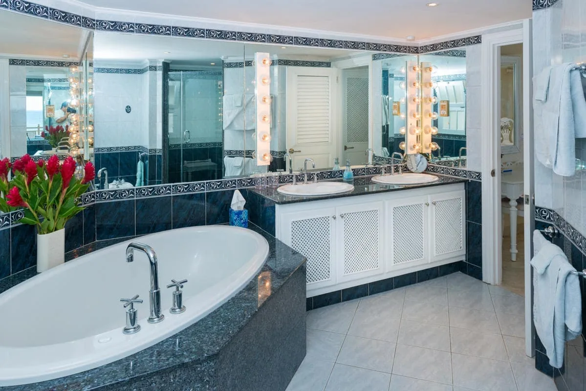 A spacious bathroom features a bathtub, a vanity, and large mirrors.