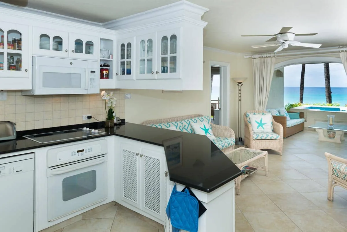 A bright kitchen opens into a sitting area beside a large window overlooking the water.
