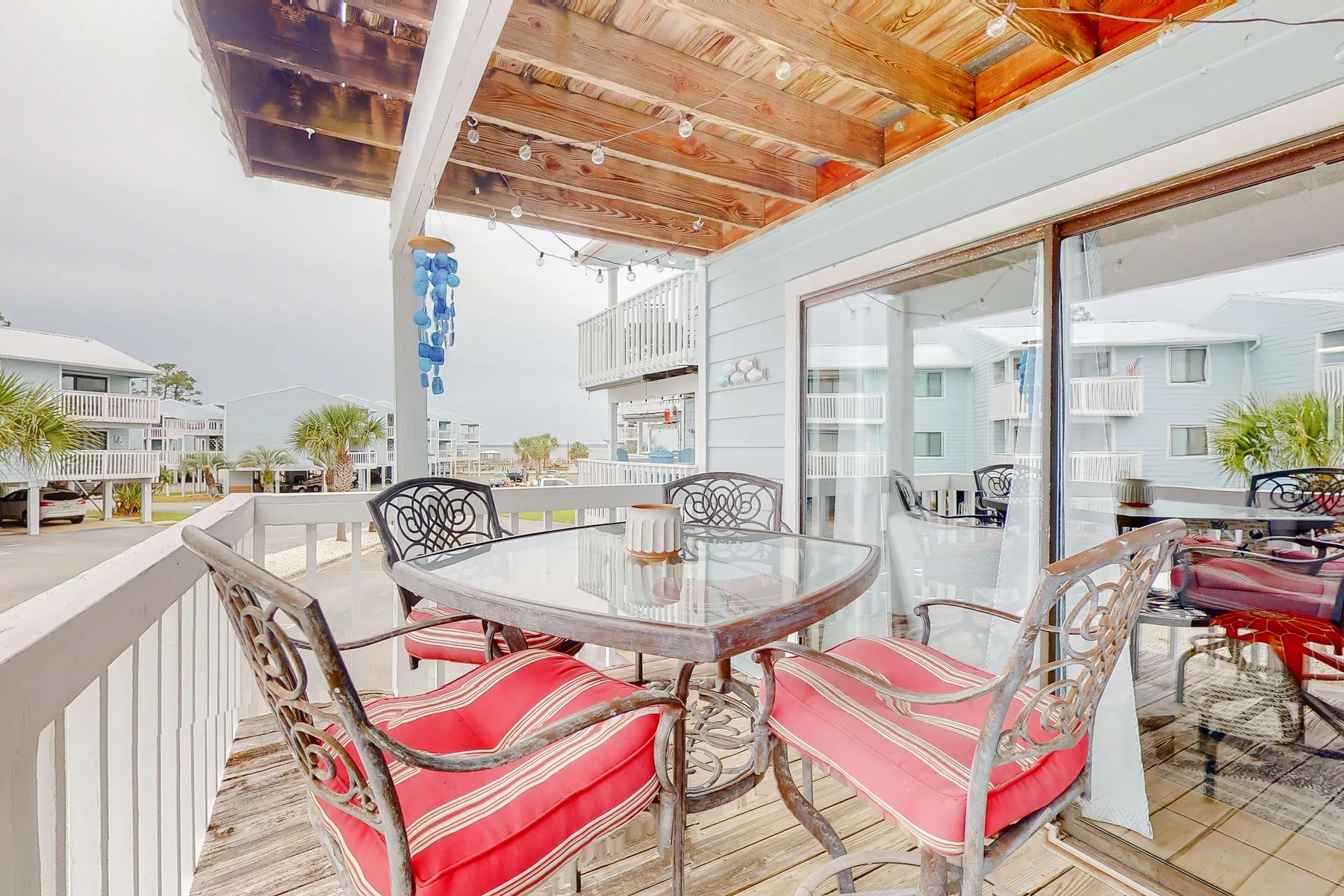 Una zona de comedor exterior cubierta con mesa y asientos acolchados da a edificios cercanos.