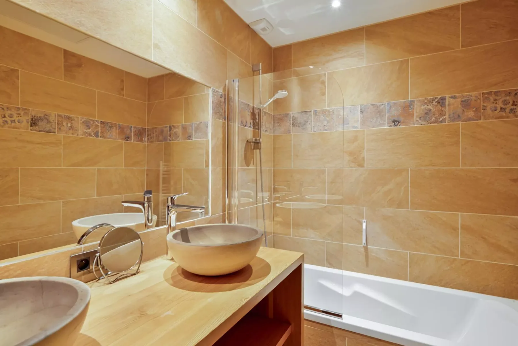 A tiled bathroom with a sink, mirror, and bathtub.