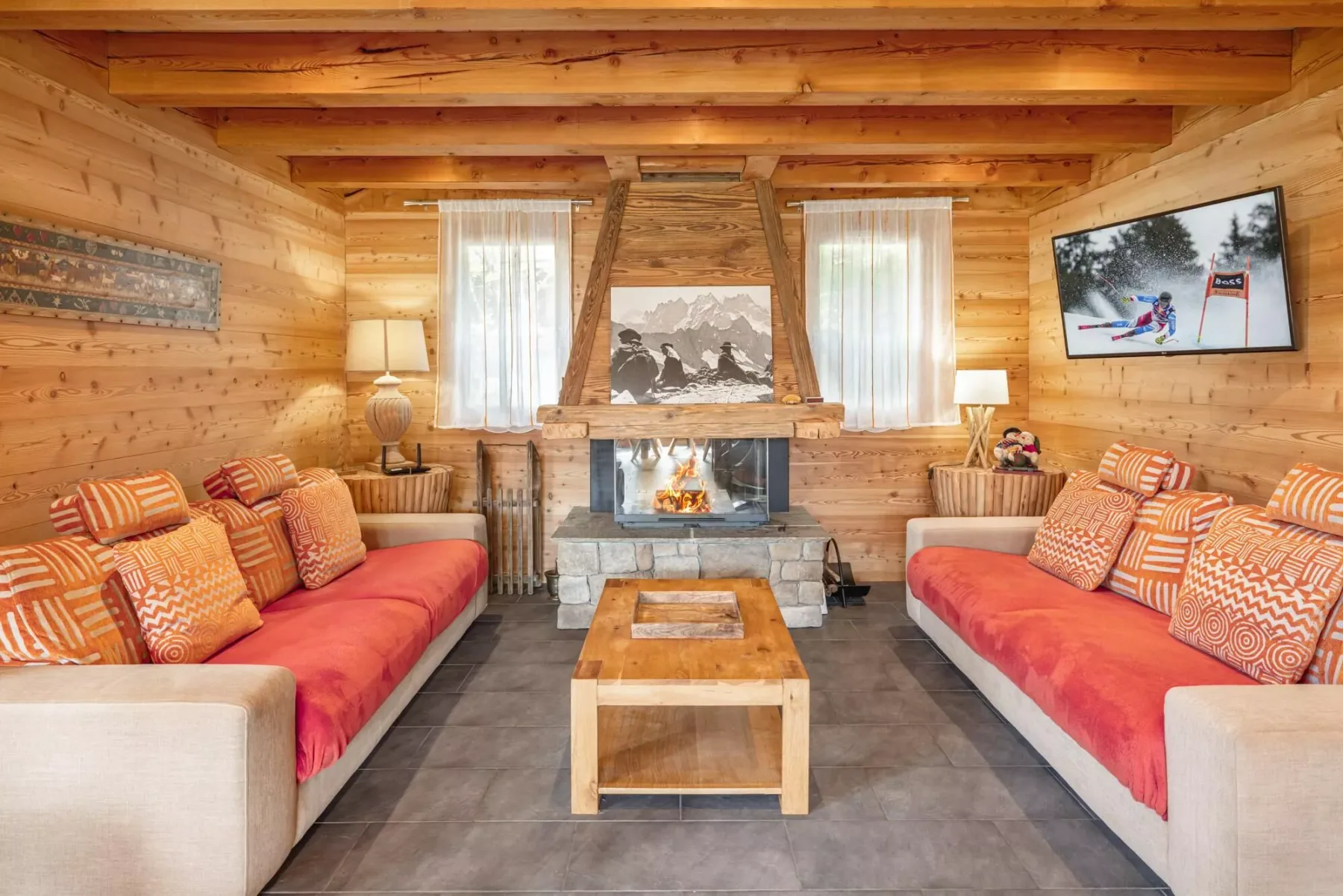 A wood-paneled living room with sofas facing a fireplace and coffee table.