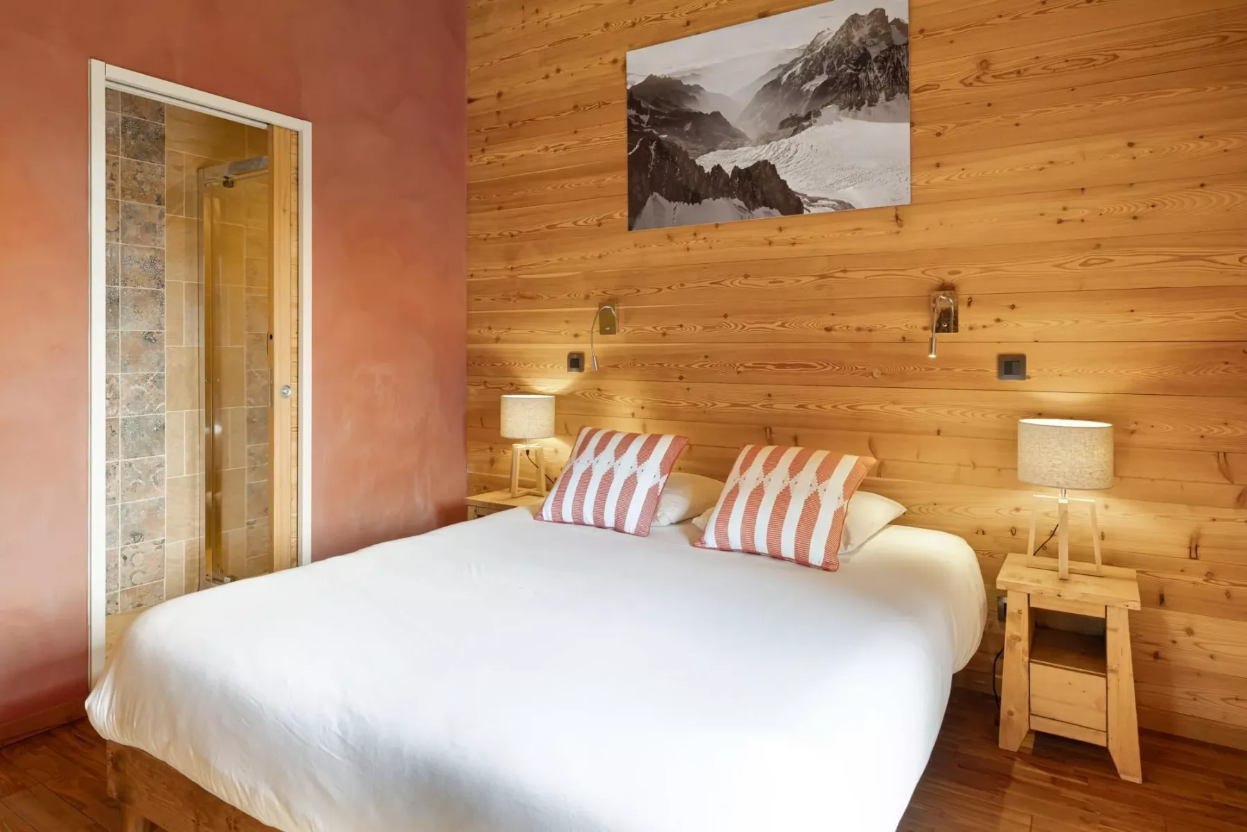 A bedroom with a large bed, striped pillows, and wood-paneled walls.