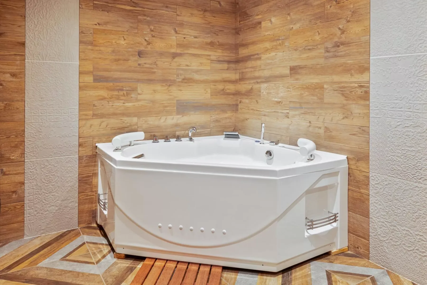A bathroom with a white corner bathtub against wood-look wall tiles.