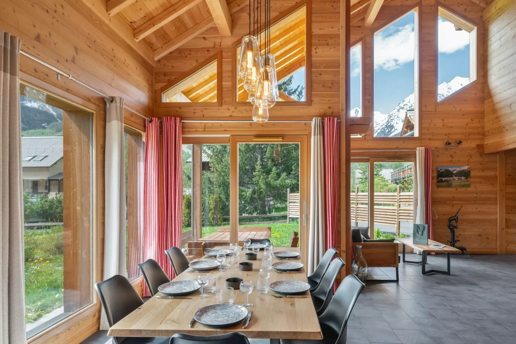 A wood-paneled dining room with a long table beside large windows.