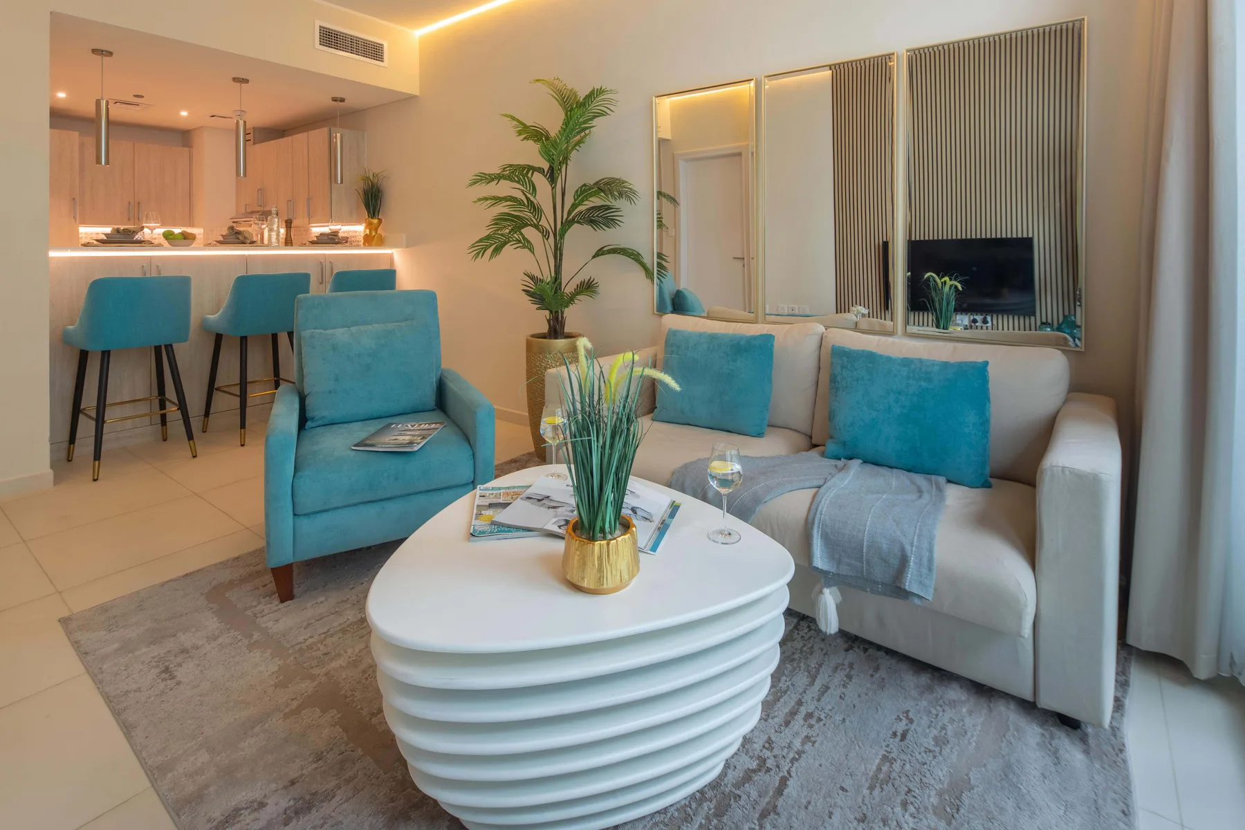 Una sala luminosa con asientos, una mesa de centro y una cocina abierta.