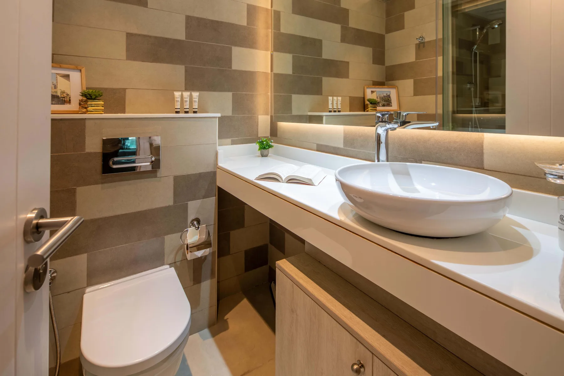A modern bathroom with a vessel sink, toilet, and tiled walls.