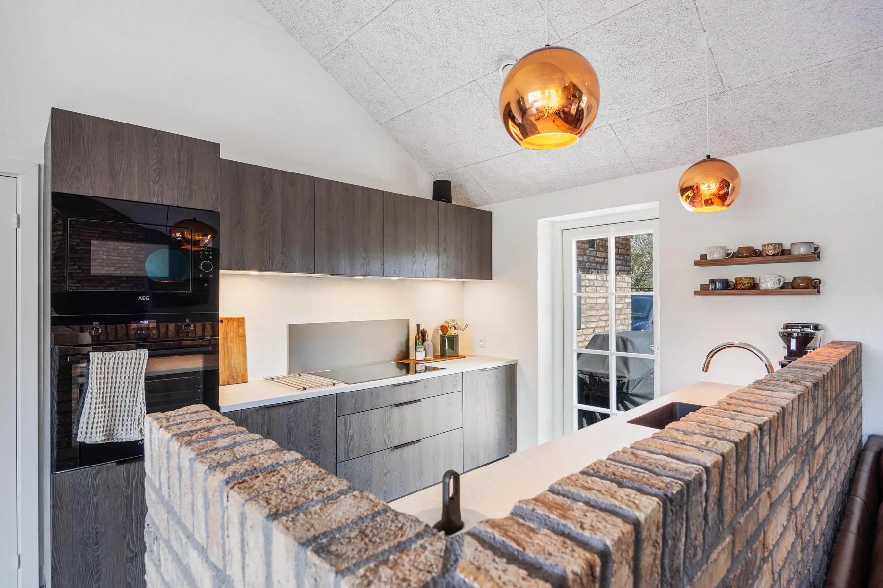A modern kitchen with dark cabinetry, a cooking area, and an island.