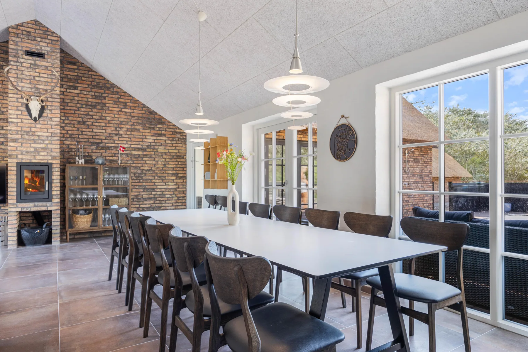 A dining room with a long table and a brick fireplace.