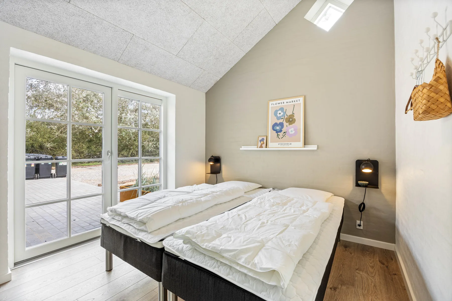 A bedroom with two beds beside large glass doors opening onto a patio.