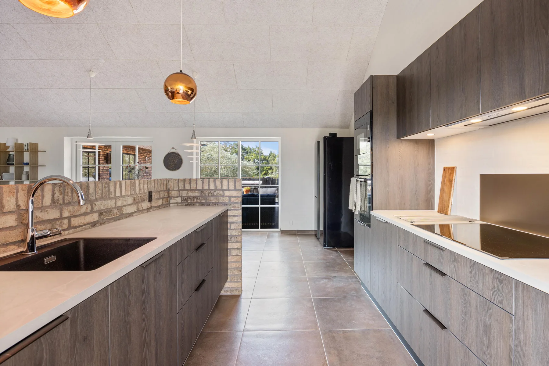 A modern kitchen with dark cabinets, stone countertops, and a central island.