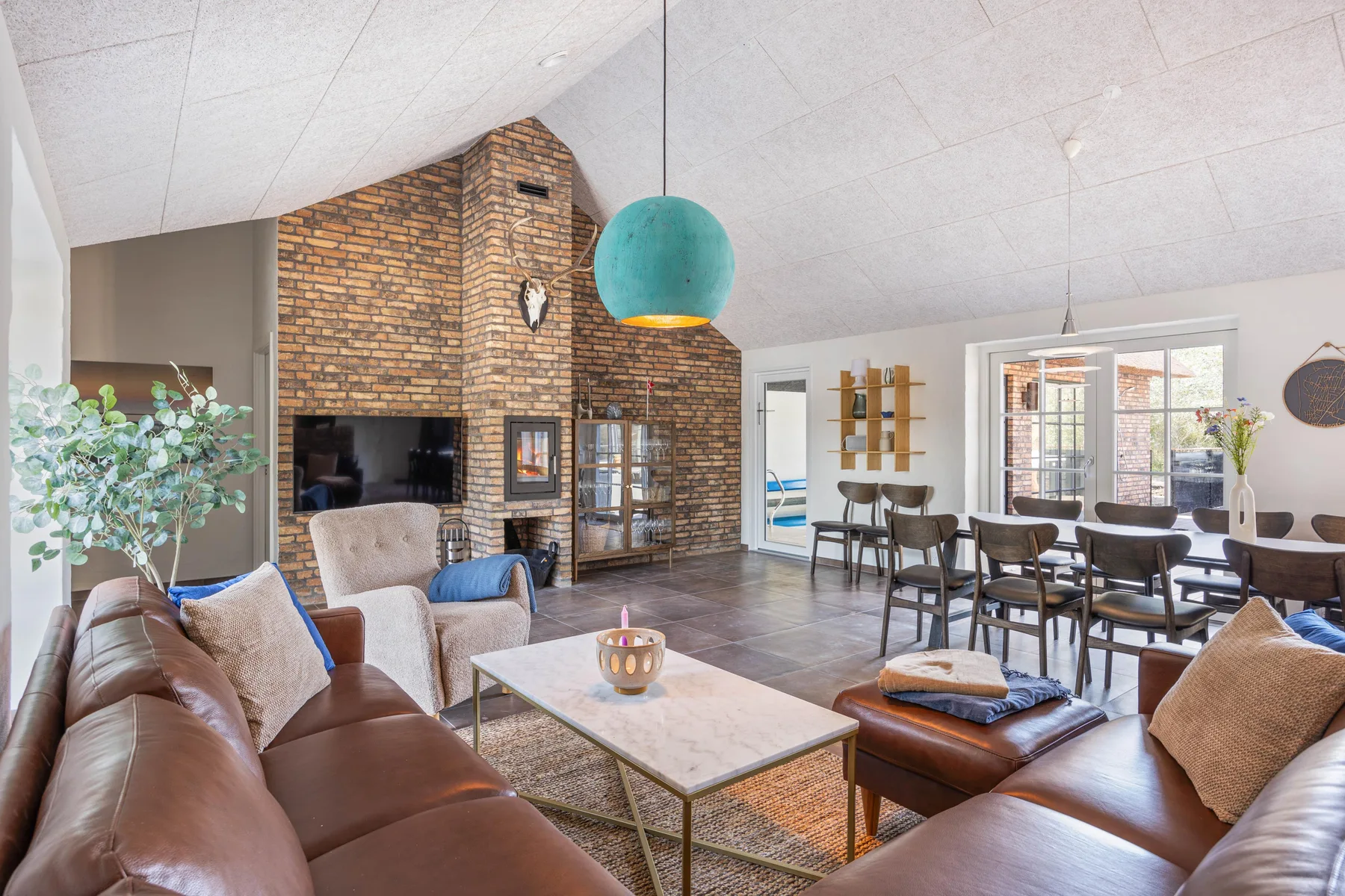 A living and dining area features leather seating and a brick fireplace.