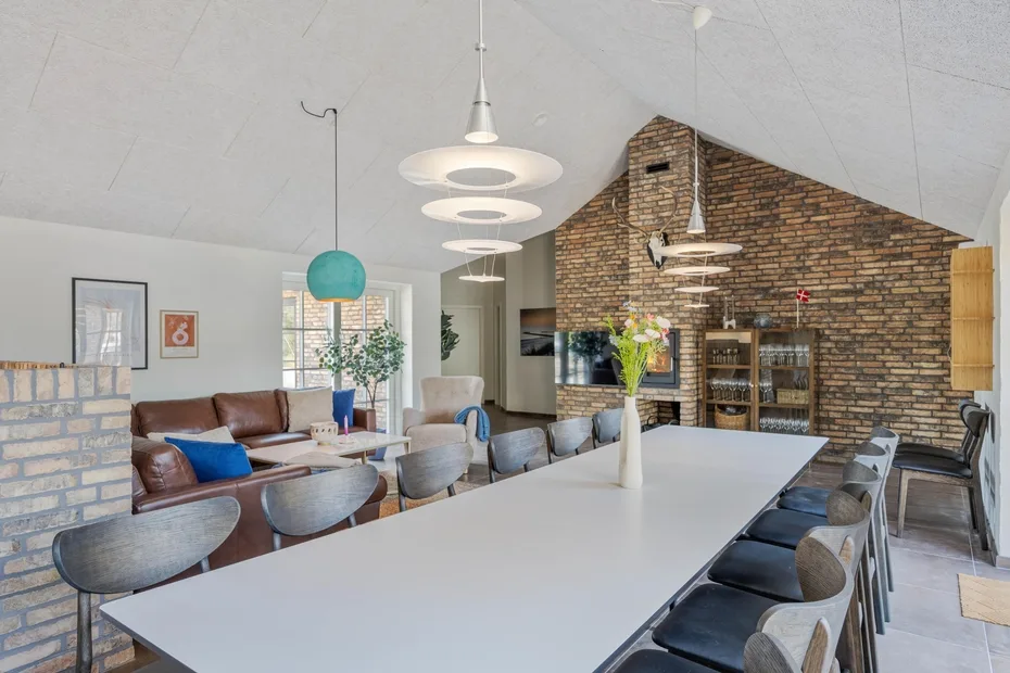 A spacious dining area features a long table beside a brick fireplace and lounge seating.