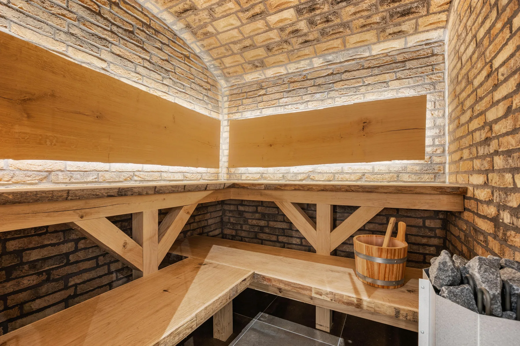 A brick sauna room with wooden benches and a stone heater.