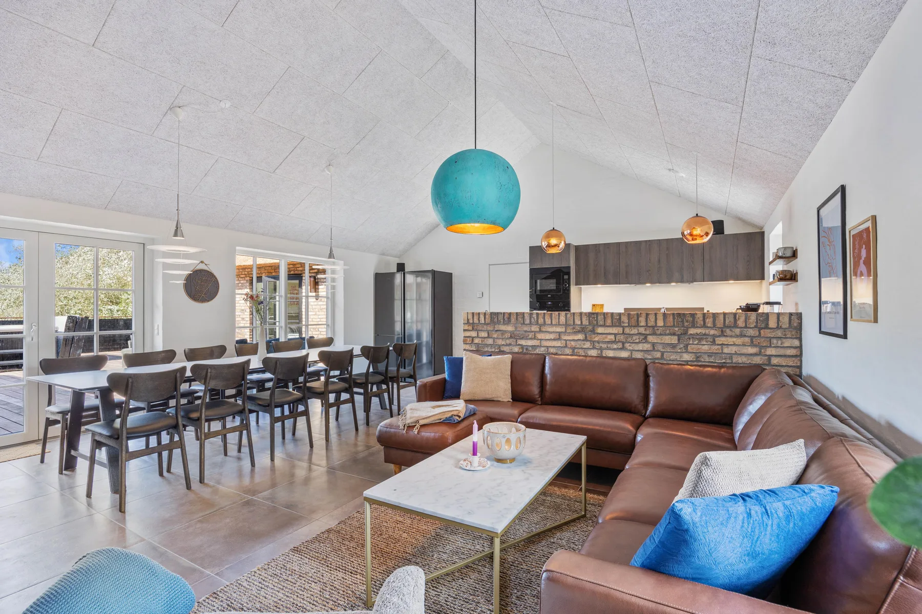 A bright open-plan living and dining area with a brown sectional and dining table.