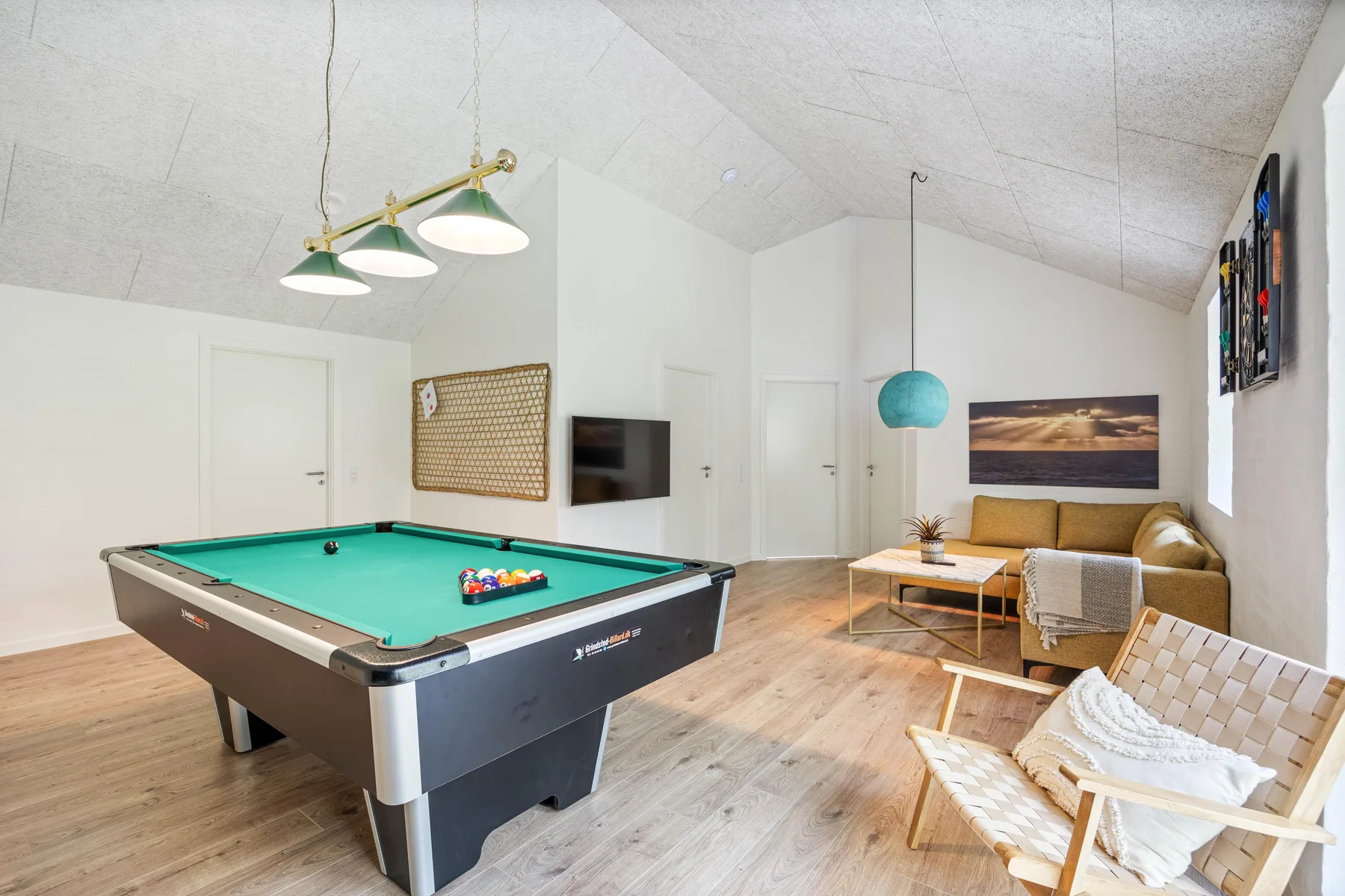 A bright recreation room features a pool table and a small seating area.