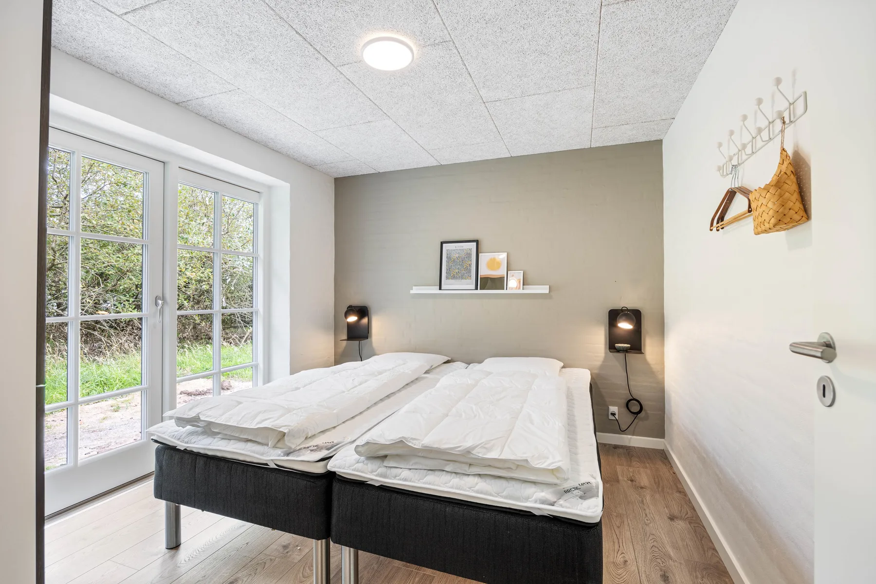 Bedroom with two beds beside large glass doors.