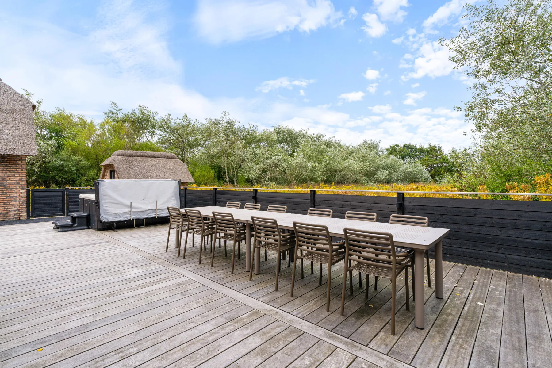 An outdoor dining area with a long table and rows of seating on a wooden deck.