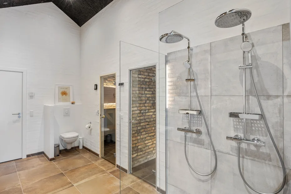 A bright bathroom with two wall-mounted shower fixtures and glass panels.